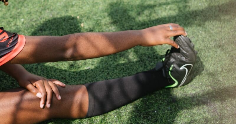 footballer stretching leg holding boot