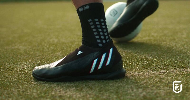 someone playing football on astro turf in black football boots